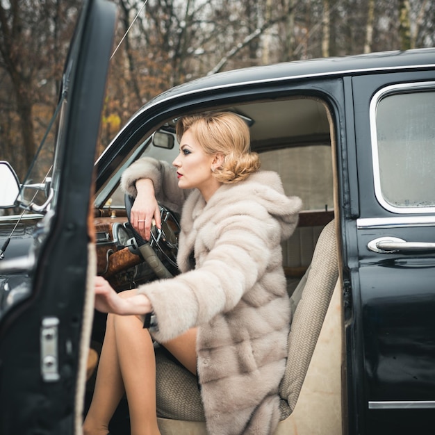 Ragazza chiamata in auto d'epoca. Viaggi e viaggi d'affari o autostop. Escort e guardia di sicurezza per donna di lusso. donna sexy in pelliccia. Auto da collezione retrò e riparazione auto da parte dell'autista