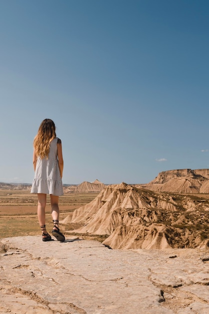Ragazza con abito in piedi nel deserto delle Bardenas Reales di Navarra in estate