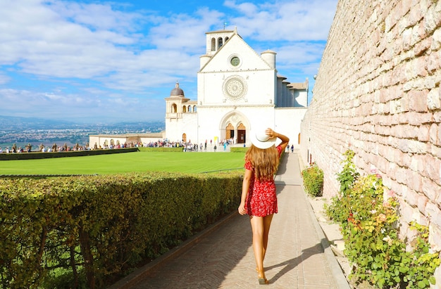 Ragazza con abito rosso con la Basilica di Assisi in Umbria, Italia