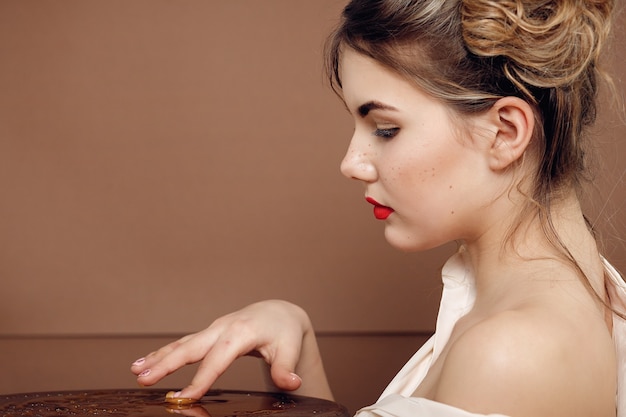 Ragazza con barattolo di miele. Concetto di cibo sano, dieta, dessert. bella ragazza sorride e tocca il miele con le mani sul tavolo