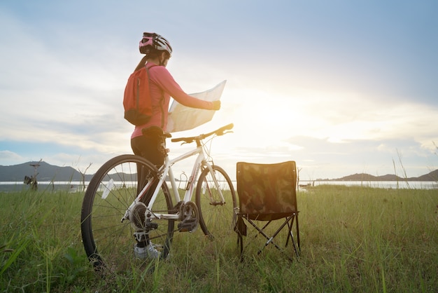 Ragazza con bici, controllando la mappa e guardandosi intorno.