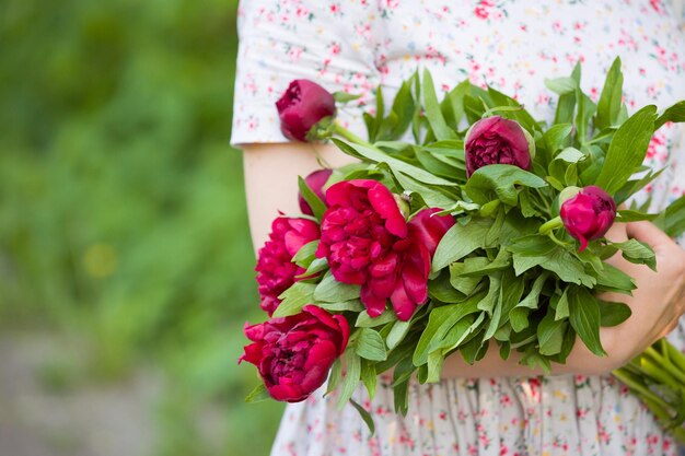 Ragazza con bouquet di fiori di peonie rosse nelle sue mani