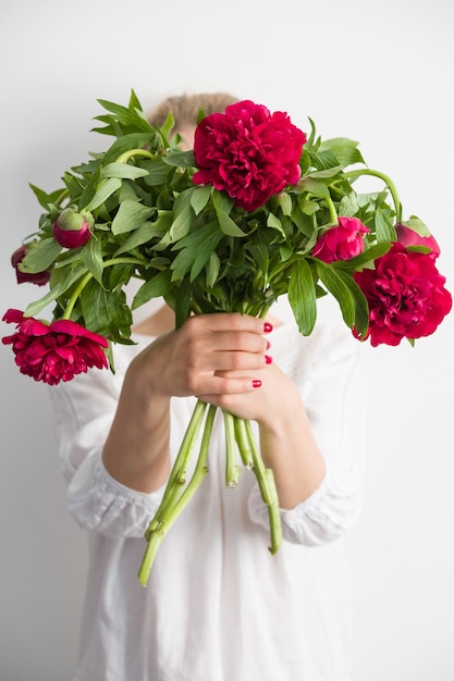 Ragazza con bouquet di fiori di peonie rosse nelle sue mani