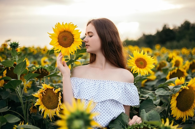 Ragazza con bouquet giallo di un campo di girasoli in fiore