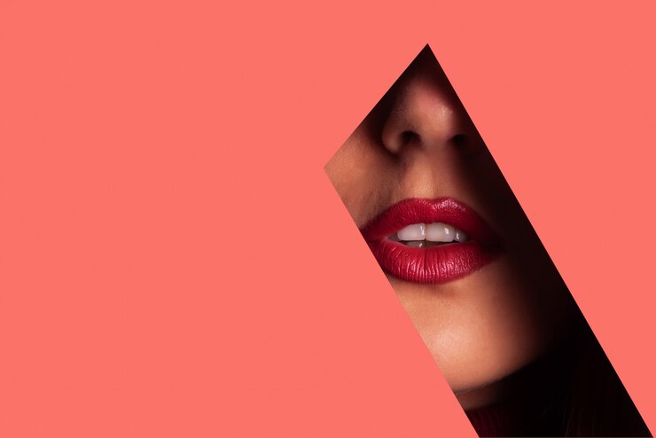 Foto ragazza con brillante trucco, rossetto rosso guardando attraverso il buco nella carta corallo vivente