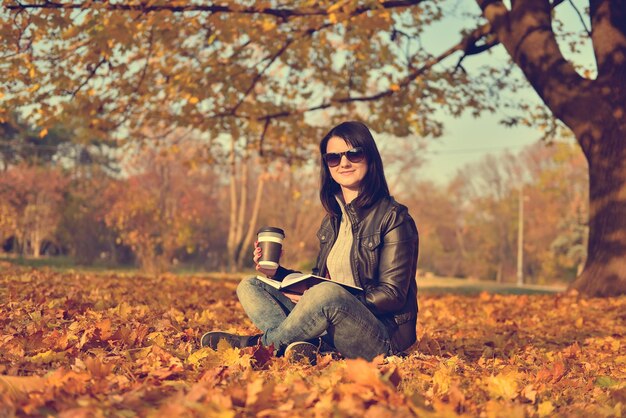 Ragazza con caffè seduto nel parco