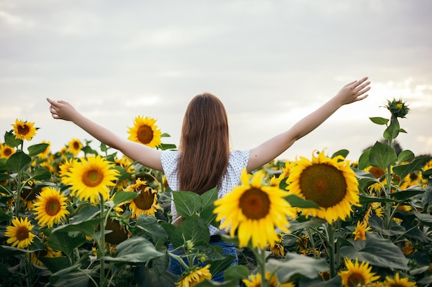 Ragazza con campo di girasoli in fiore giallo