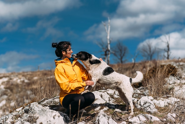 Ragazza con cane che cammina in montagna. Amico canino. A spasso con il tuo animale domestico. In viaggio con un cane. Un animale domestico. Cane intelligente. Migliore amico. Il cane si lecca la faccia.