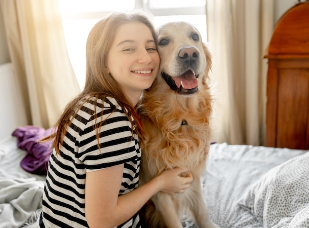 Ragazza con cane golden retriever a letto