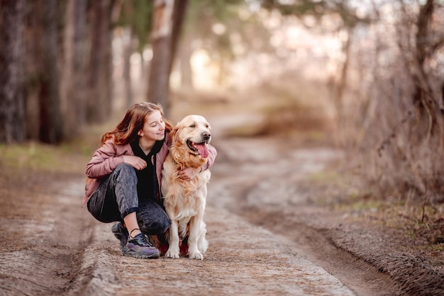 Ragazza con cane golden retriever nel bosco