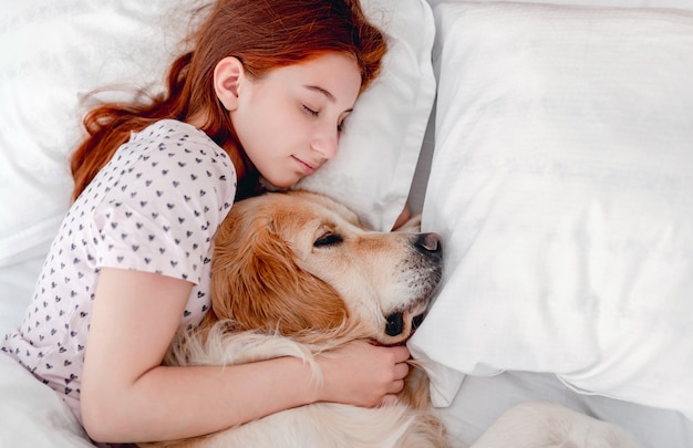 Ragazza con cane golden retriever nel letto