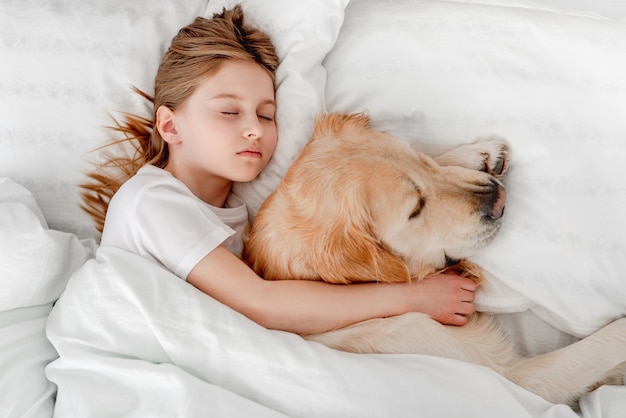 Ragazza con cane golden retriever nel letto