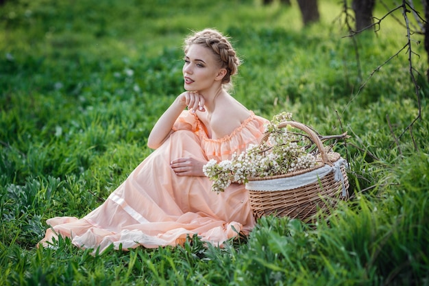 Ragazza con capelli biondi in un vestito leggero nel giardino fiorito. concetto di moda primavera femminile.