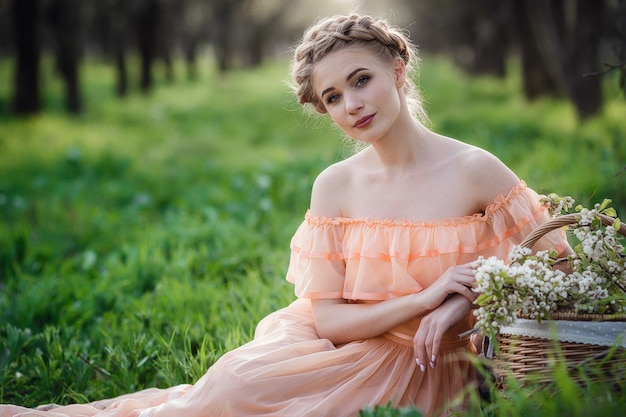 Ragazza con capelli biondi in un vestito leggero nel giardino fiorito. concetto di moda primavera femminile.