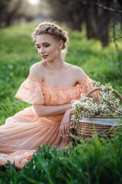 Ragazza con capelli biondi in un vestito leggero nel giardino fiorito. concetto di moda primavera femminile.