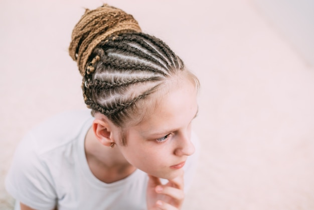 Ragazza con capelli castani e trecce intrecciate con capelli artificiali