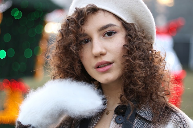 Ragazza con capelli ricci che tengono i guanti bianchi al natale giusto