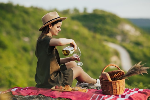 ragazza con cappello che versa vino nel bicchiere