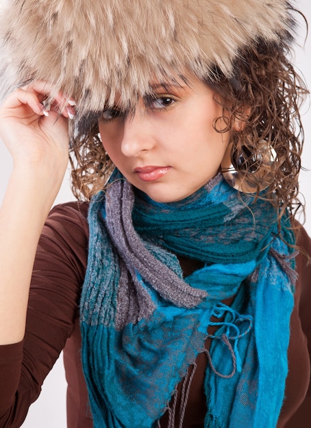 Ragazza con cappello di pelliccia e sciarpa blu isolata su sfondo bianco