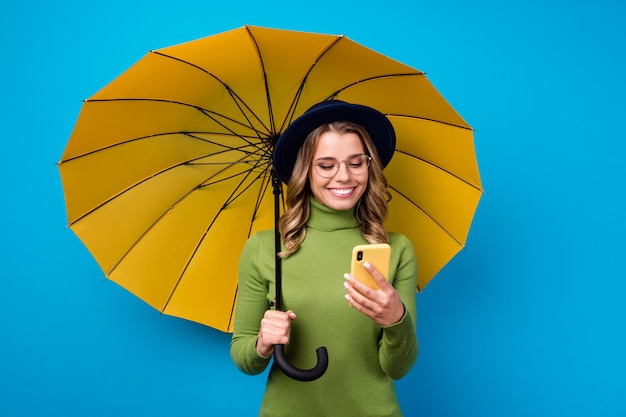 ragazza con cappello e occhiali tenendo ombrello e telefono