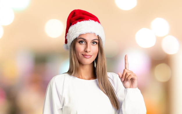 Ragazza con cappello natale indicando con il dito indice una grande idea sul muro sfocato