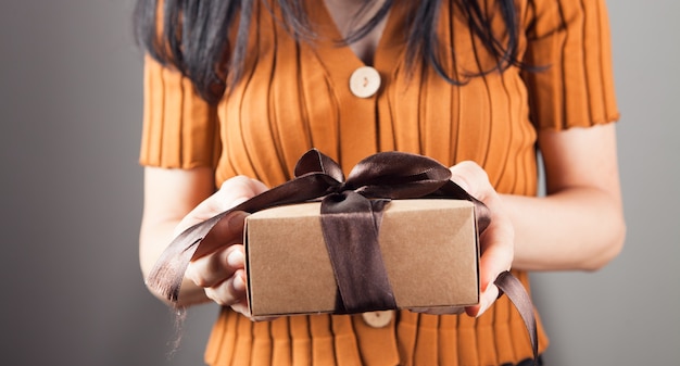 Ragazza con confezione regalo su sfondo grigio