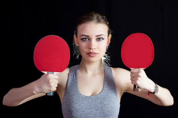 Ragazza con due racchette per giocare a ping-pong.