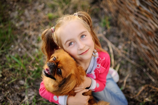 Ragazza con gli amici del cane sull'erba nel parco