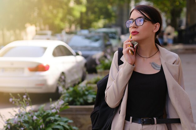 Ragazza con gli occhiali che parla al telefono camminando per strada