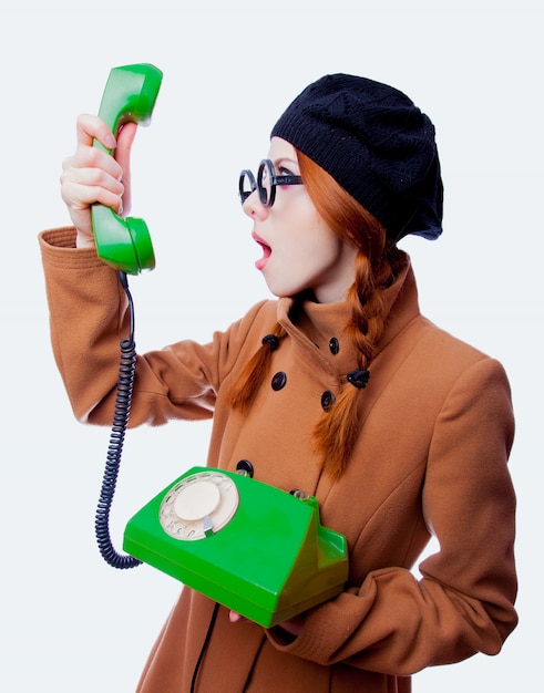 Ragazza con gli occhiali e il cappotto che parla dal telefono