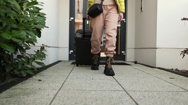 Ragazza con gli stivali che cammina con i bagagli da casa