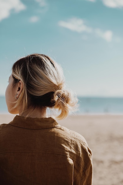 Ragazza con i capelli corti seduta sulla spiaggia