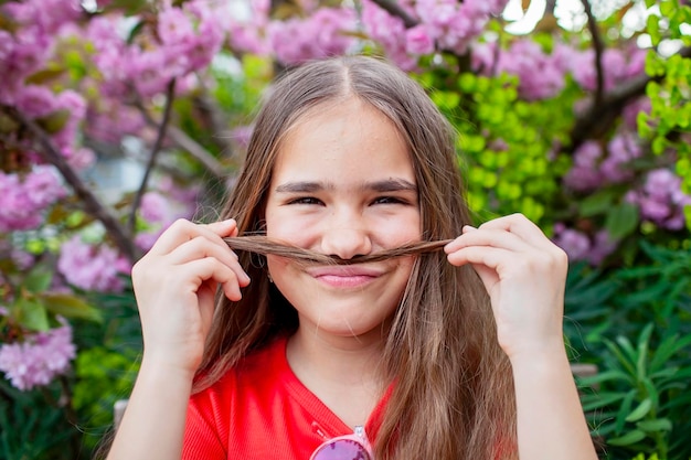 Ragazza con i capelli e i baffi in mezzo a fiori rosa