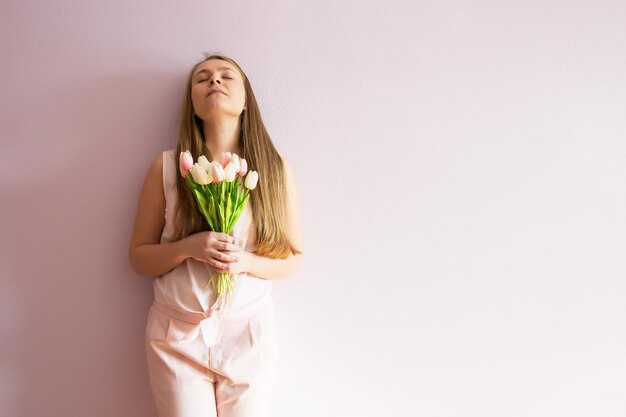 ragazza con i capelli lunghi biondi sciolti un cappello di feltro in testa tiene i fiori di primavera nelle sue mani