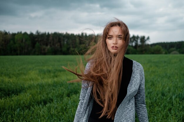 Ragazza con i capelli lunghi in piedi nel campo al vento Il concetto di libertà e passione