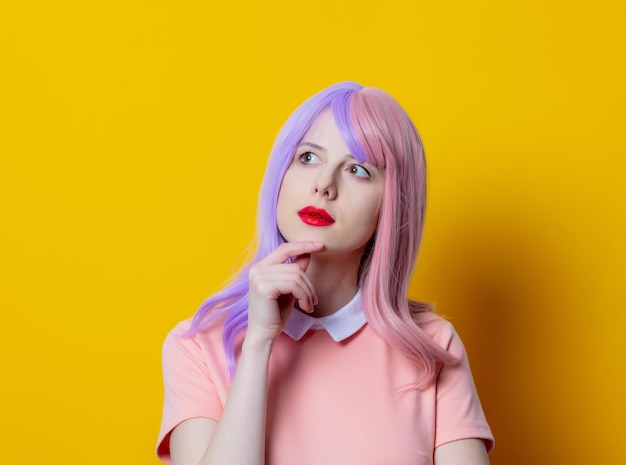 Ragazza con i capelli viola e vestito rosa su sfondo giallo