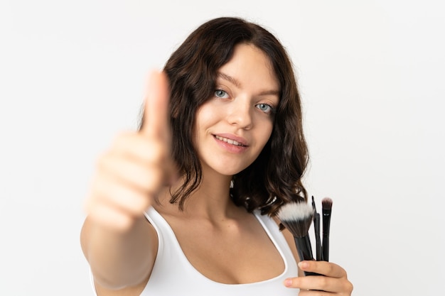 Ragazza con i pennelli trucco isolati su bianco