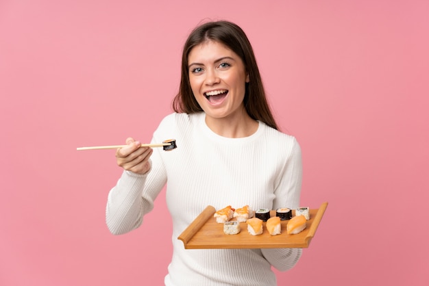 Ragazza con i sushi sopra la parete rosa isolata