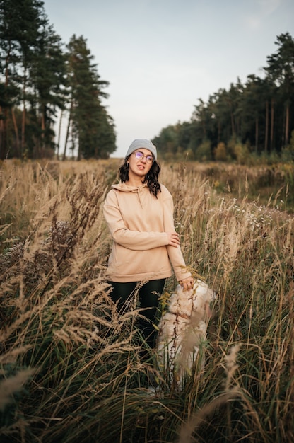 Ragazza con il cane golden retriever che cammina sulla strada forestale