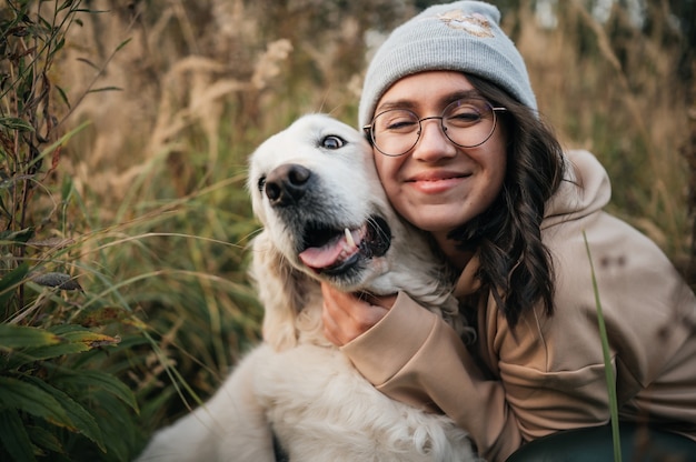 Ragazza con il cane golden retriever che cammina sulla strada forestale