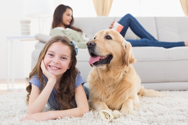 Ragazza con il cane sul tappeto mentre madre rilassante a casa