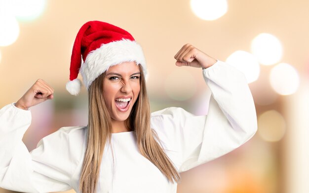 Ragazza con il cappello di natale che celebra una vittoria sopra la parete unfocused