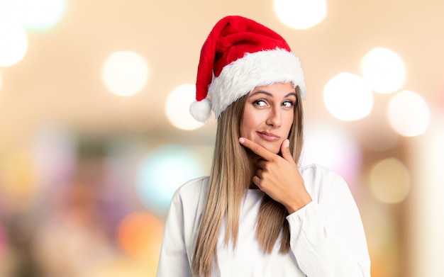 Ragazza con il cappello di natale che pensa un'idea sopra la parete unfocused