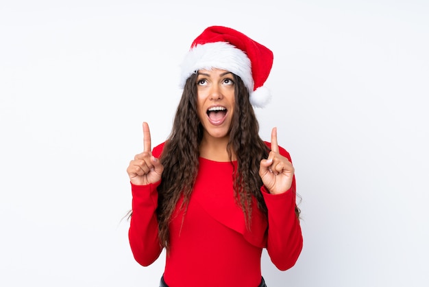 Ragazza con il cappello di natale sopra fondo bianco isolato che indica con il dito indice una grande idea