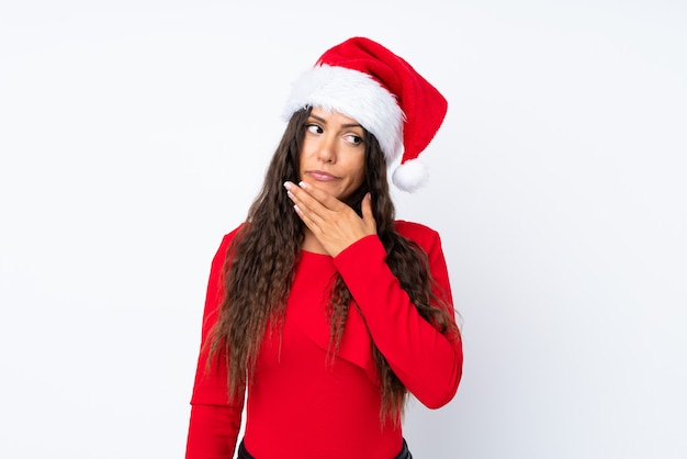 Ragazza con il cappello di natale sopra fondo bianco isolato che pensa un'idea