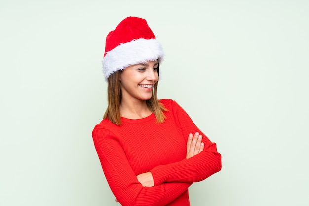 Ragazza con il cappello di natale sopra la risata verde isolata