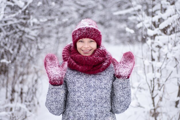 Ragazza con il cappello rosso e una sciarpa divertendosi nel parco invernale.