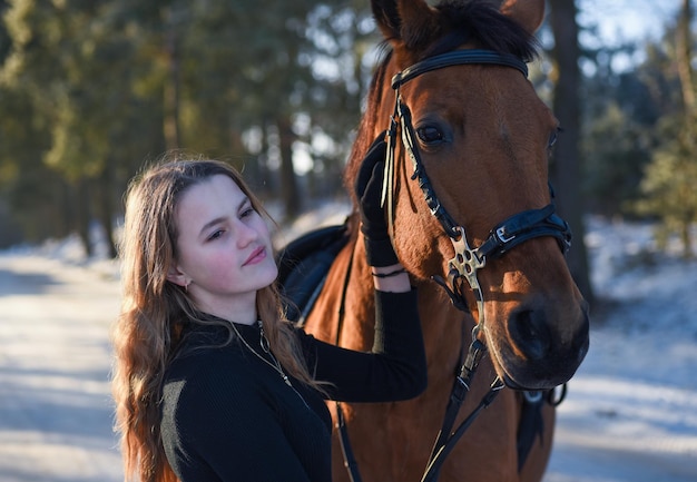 Ragazza con il cavallo sulla strada forestale di inverno.