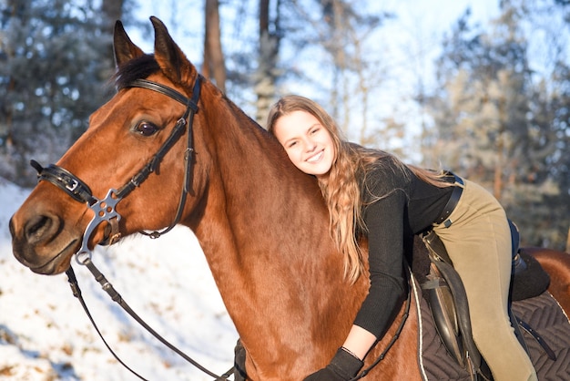 Ragazza con il cavallo sulla strada forestale di inverno.