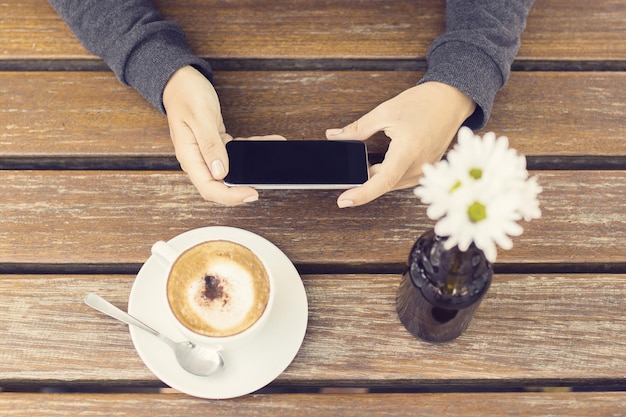 Ragazza con il cellulare e la tazza di caffè